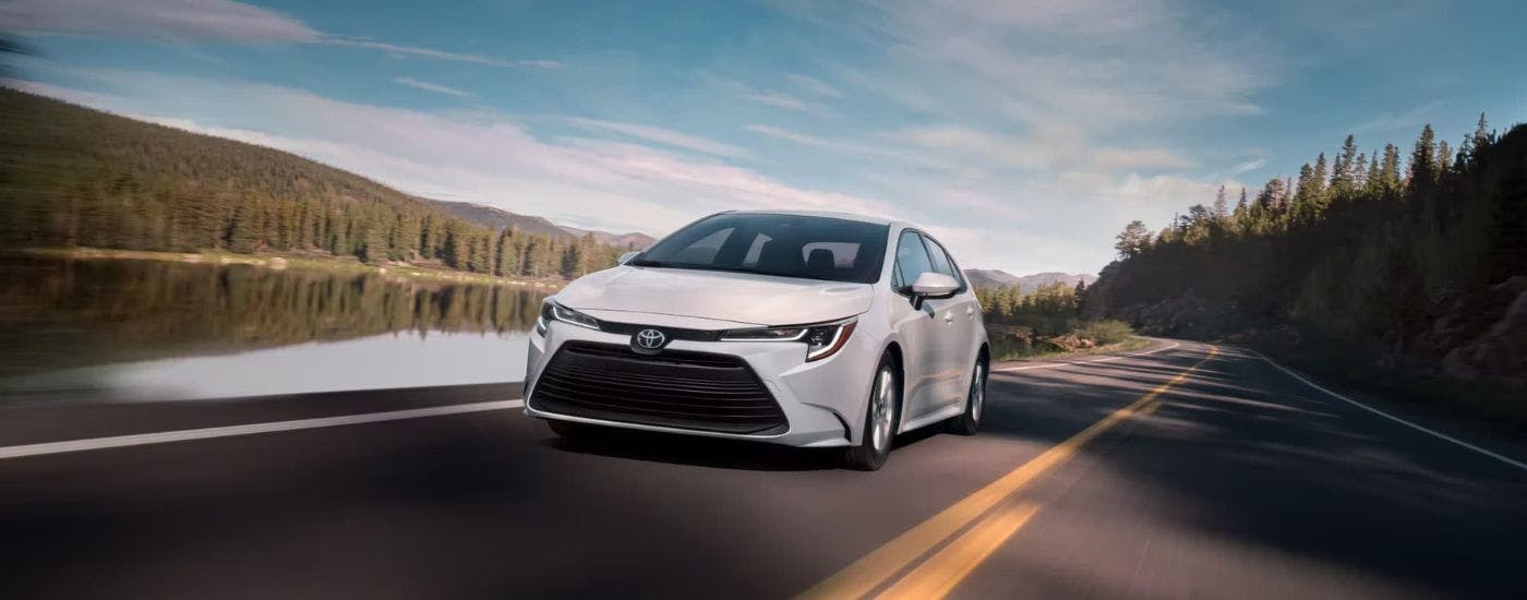 White 2023 Toyota Corolla driving down a rural road