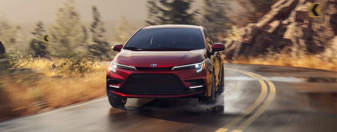 Red 2025 Toyota Corolla Hybrid for sale near Sandy Springs rounding a corner