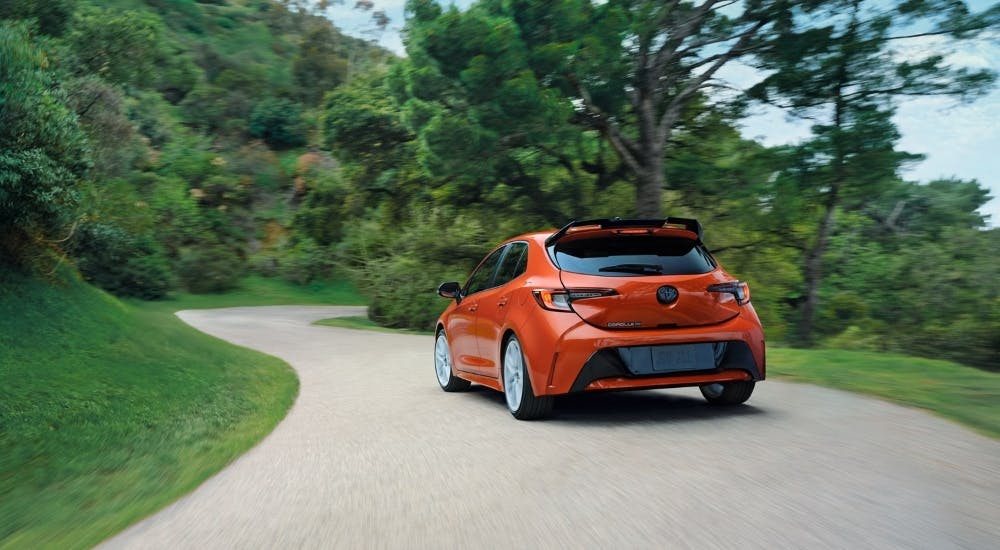 Orange 2026 Toyota Corolla FX Hatchback driving on a winding road