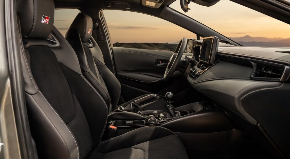 The black interior of a 2025 Toyota GR Corolla is shown from the passenger side.