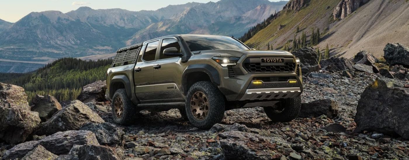 Green 2024 Toyota Tacoma iForceMAX Trailhunter parked on a rocky mountain