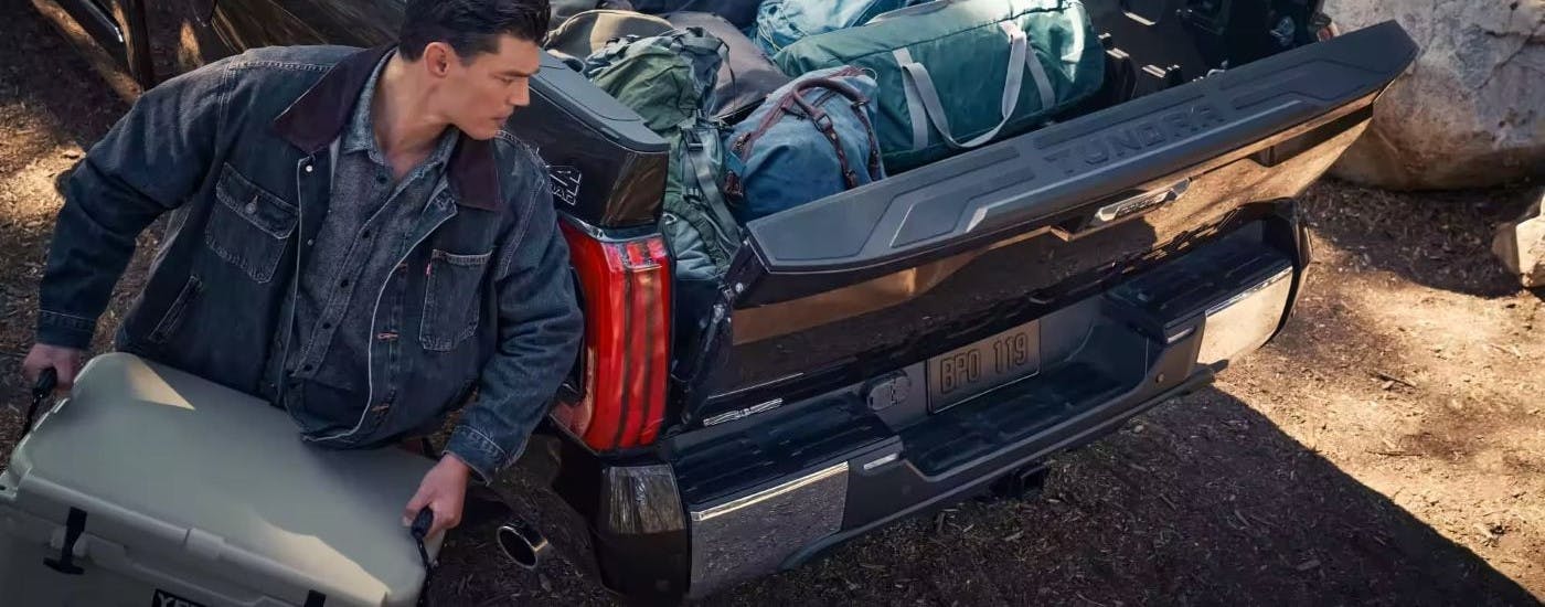 Person loading gear into a dark blue 2023 Toyota Tundra 1794 Edition