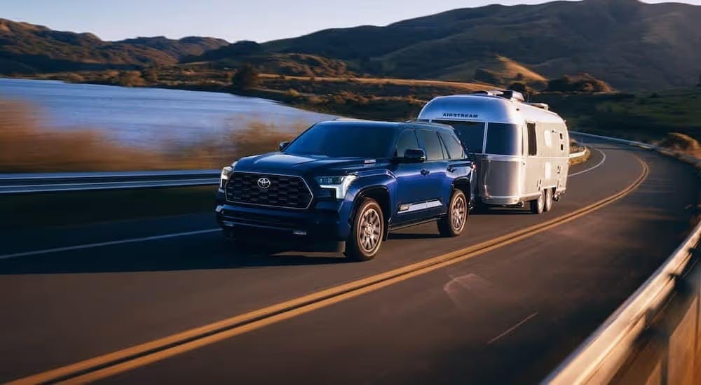 A blue 2024 Toyota Sequoia Platinum is shown towing a trailer to a Toyota dealer near Powder Springs.