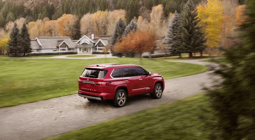 A red 2024 Toyota Sequoia driving through a neighborhood.