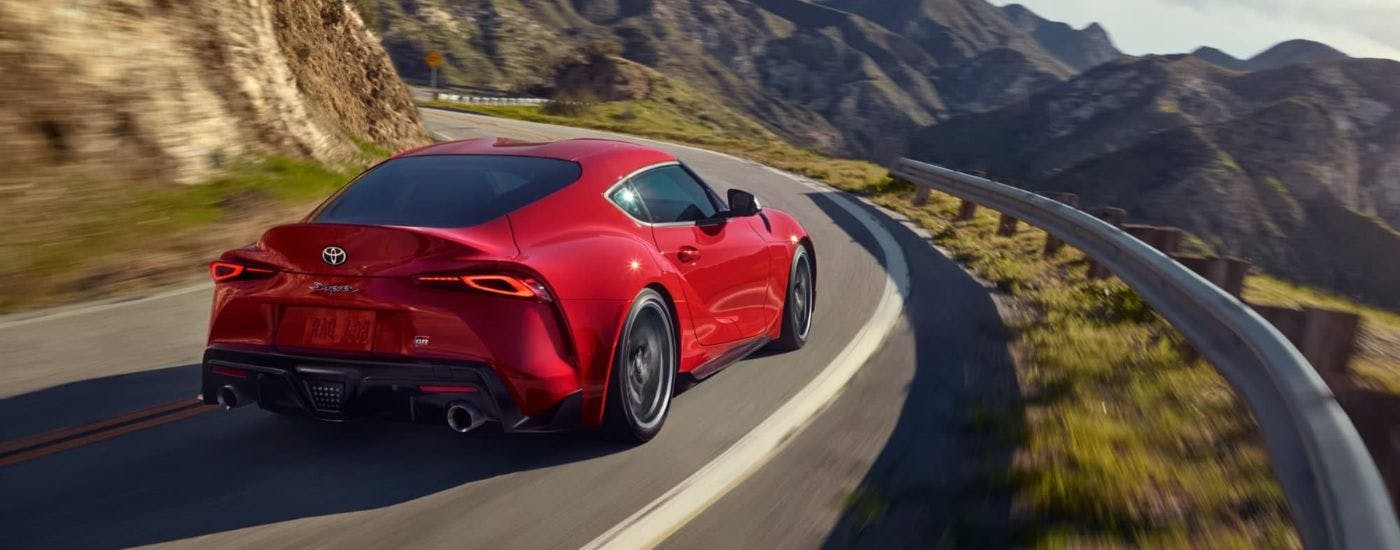 Red 2023 Toyota GR Supra driving on a winding road