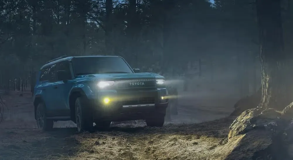 A blue 2024 Toyota Land Cruiser is shown driving at night.