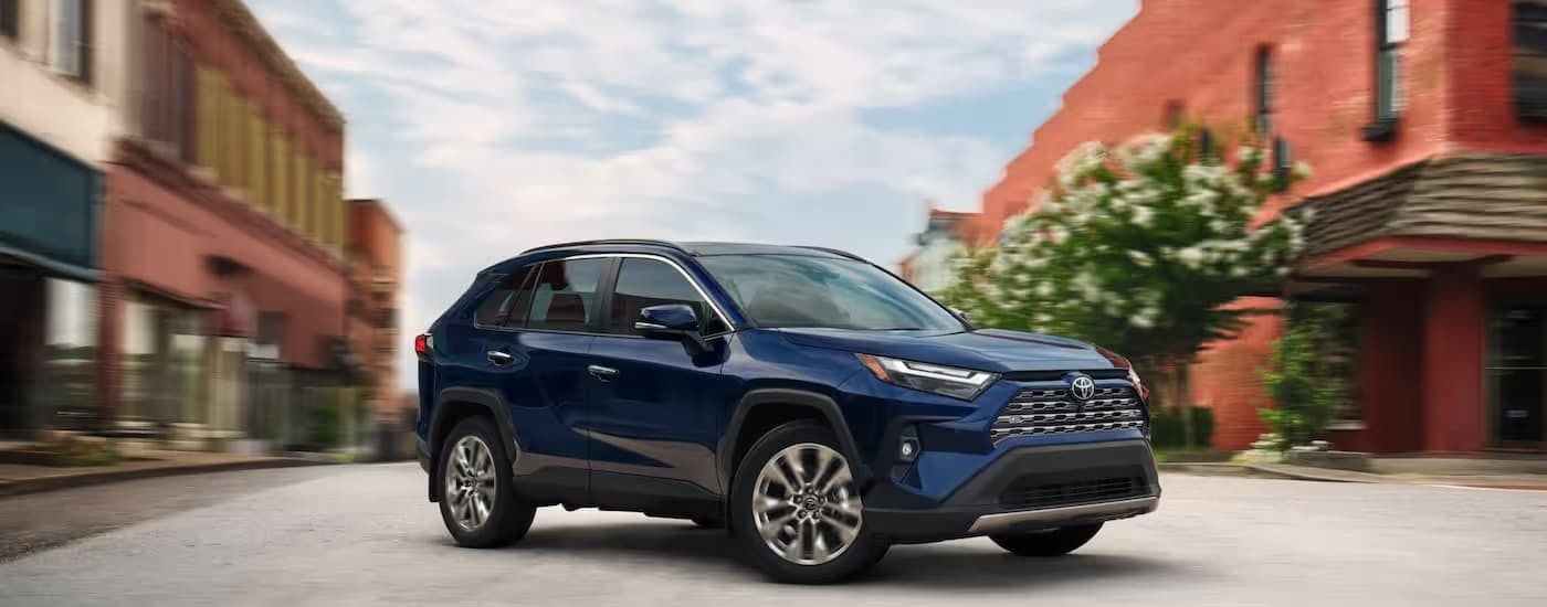 Side of a dark blue 2025 Toyota RAV4 for sale near Atlanta parked on a street.