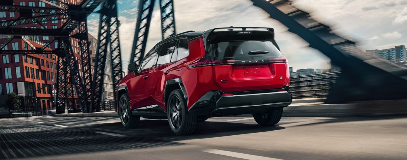 Red 2026 Toyota RAV4 PHEV GR Sport driving over a bridge