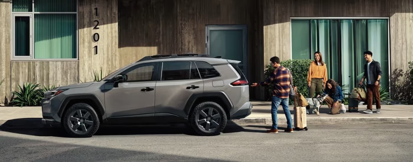 Side of a grey 2025 Toyota RAV4 for sale near Sandy Springs parked near a house.