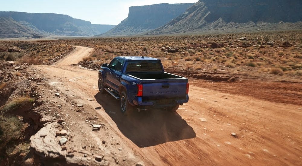 Blue 2025 Toyota Tacoma driving on a trail