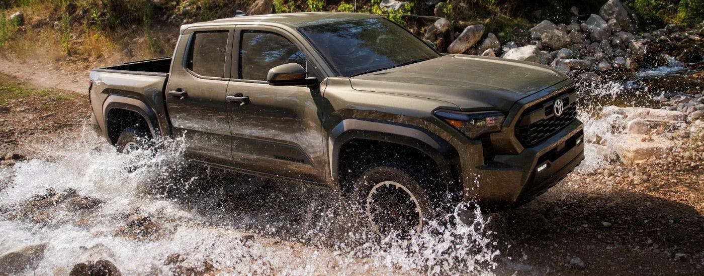 Green 2025 Toyota Tacoma off-roading through water