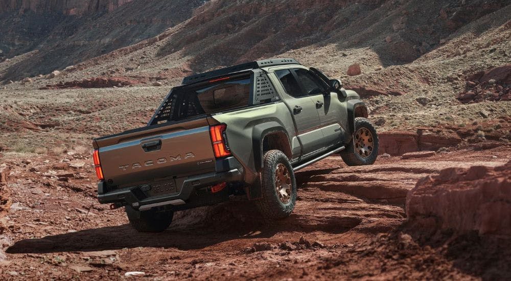 A green 2025 Toyota Tacoma Trailhunter is shown from the rear at an angle.