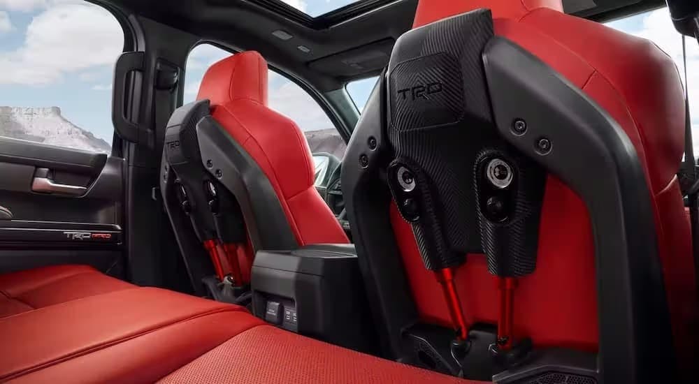 The red interior of a 2024 Toyota Tacoma TRD Pro is shown from the back seat.