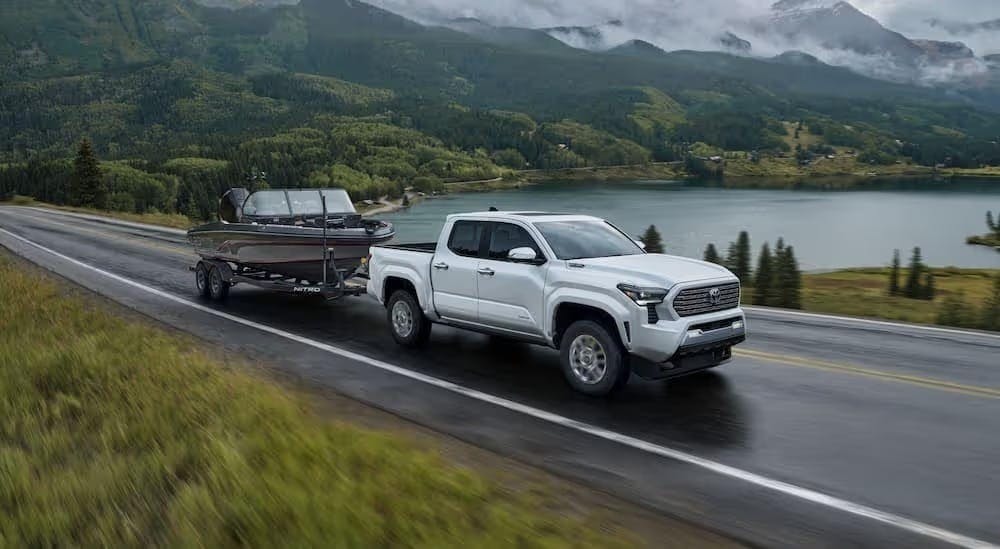 A white 2024 Toyota Tacoma Limited is shown towing a boat after viewing a Toyota Tacoma for sale nea…