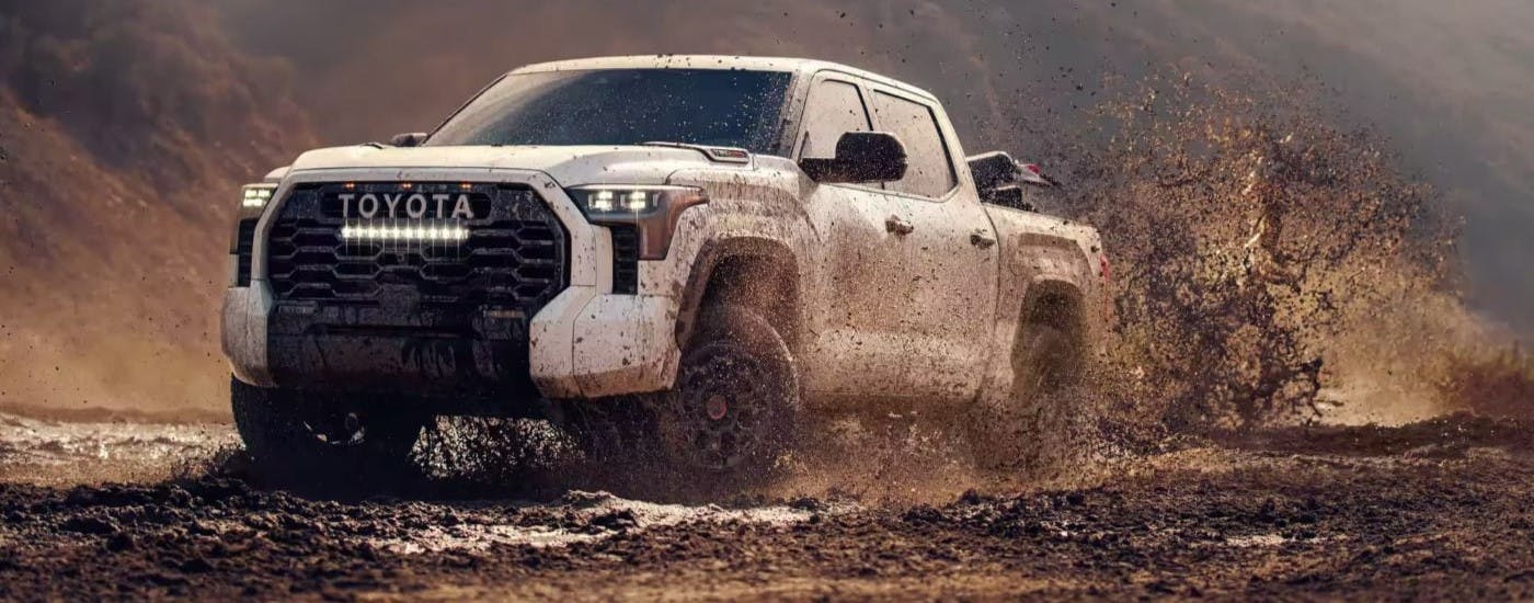 White 2024 Toyota Tundra TRD Pro driving over a mud puddle.