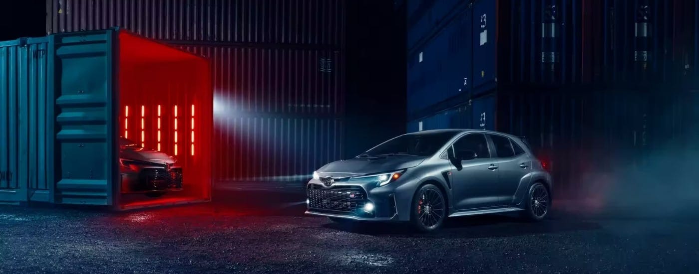 Silver 2023 Toyota GR Corolla parked near a shipping container at night
