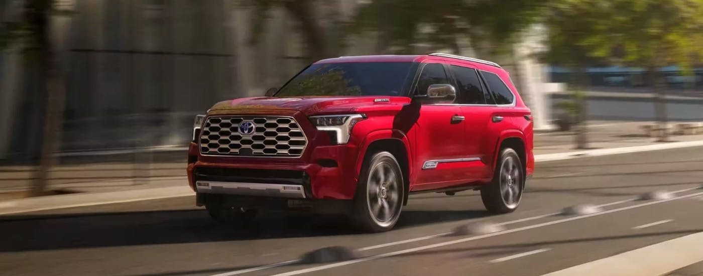 Red 2024 Toyota Sequoia driving to look at Toyotas for sale near Smyrna