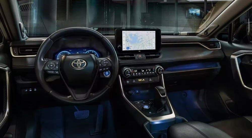 The black interior of a 2023 Toyota RAV4 is shown from the driver's seat.