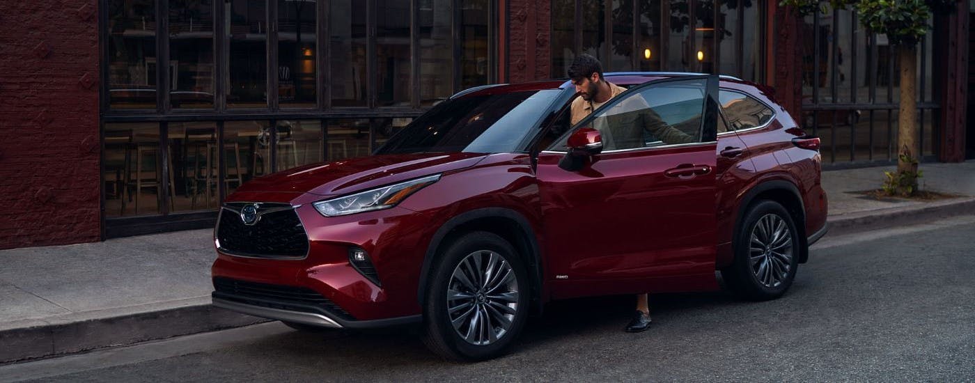Red 2023 used Toyota Highlander for sale parked near a city curb