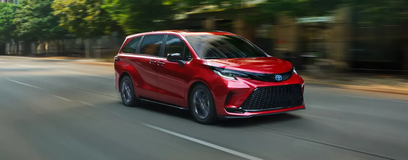 Red 2026 Toyota Sienna driving down an open road.