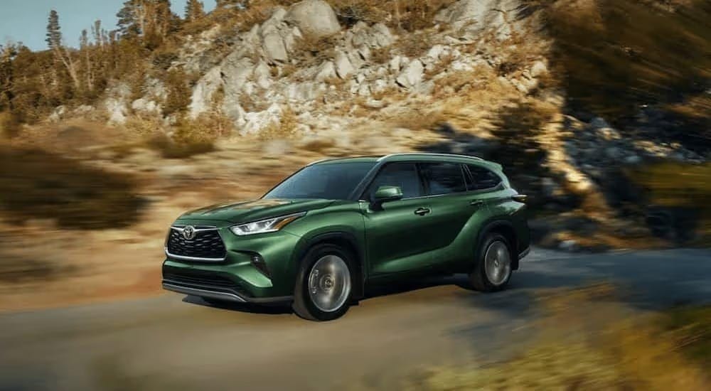 A green 2023 Toyota Highlander is shown driving on a road after visiting a used Toyota dealer near Fair Oaks.