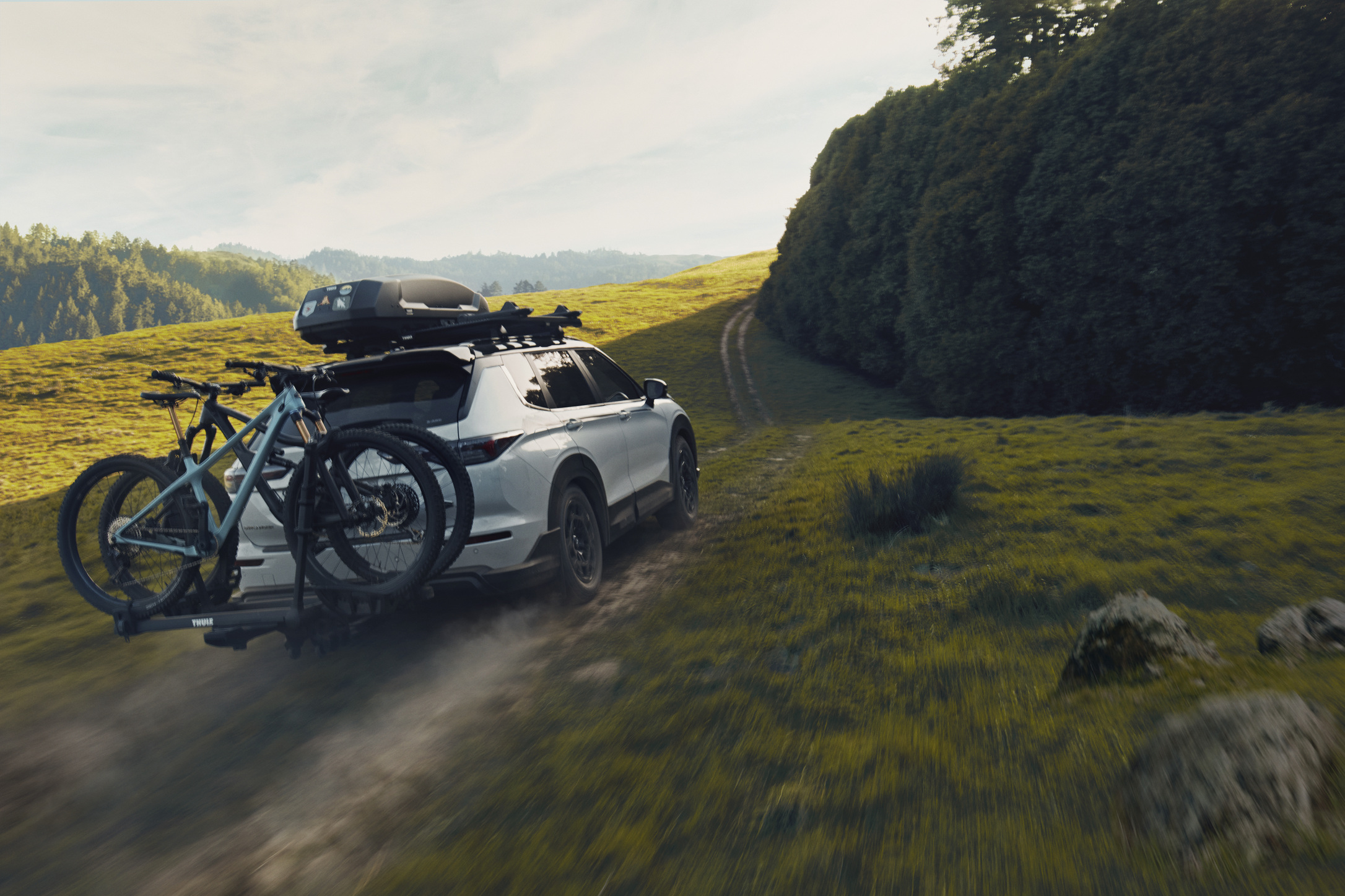 Back of White Mitsubishi Outlander Trail with bikes and roof rack