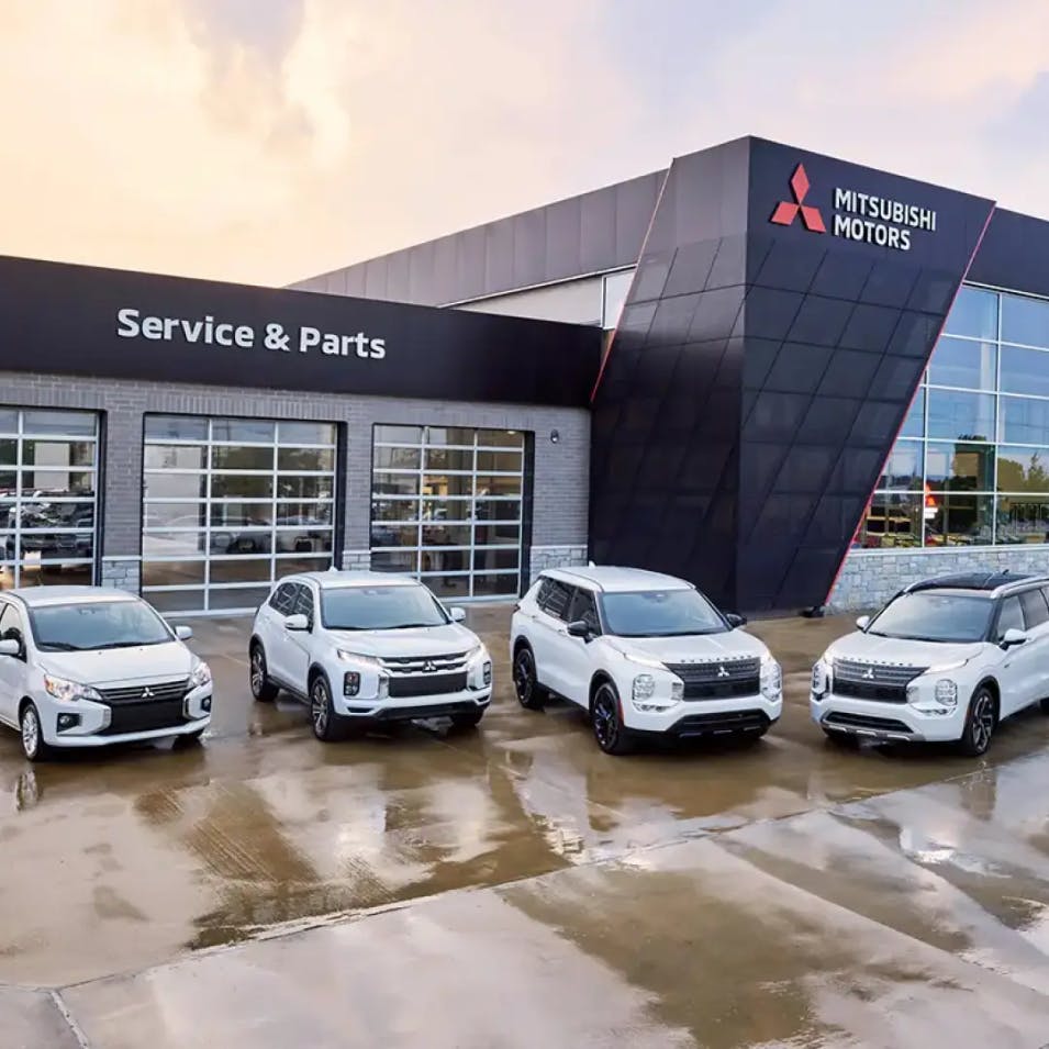 The Mitsubishi line up in front of a Mitsubishi store
