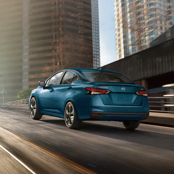 2025-nissan-versa-driving-down-city-highway-tall-skyscrapers-background
