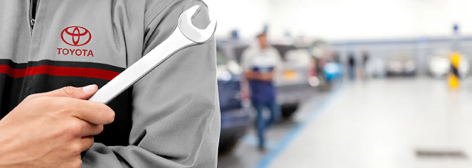 Toyota service technician holding a wrench inside a service center