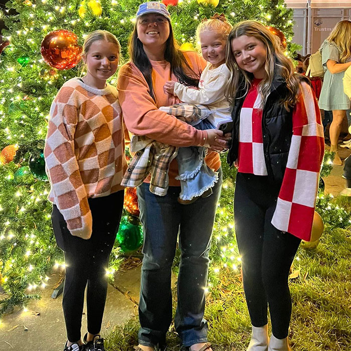family poses for a group picture in front of a lit Christmas tree