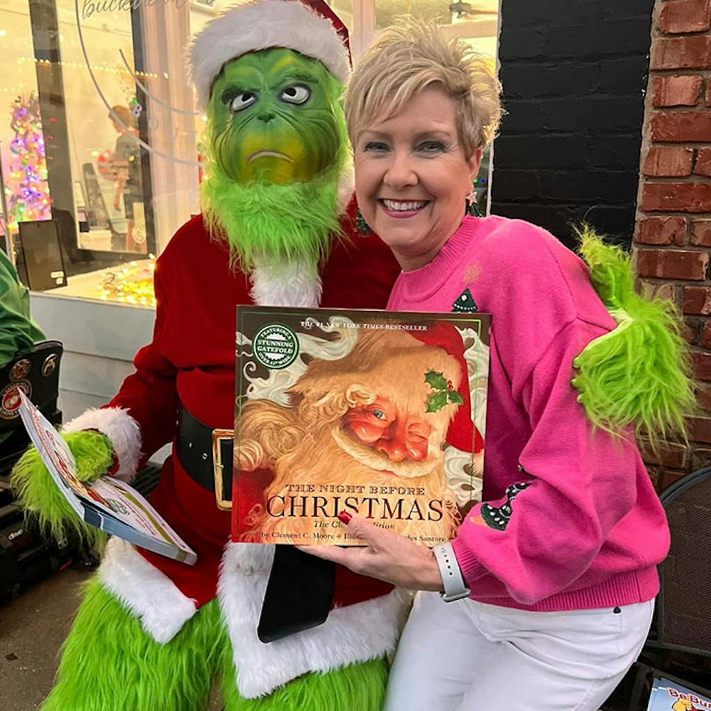the grinch and women The Grinch sits with a women holding a book in front of a store display case