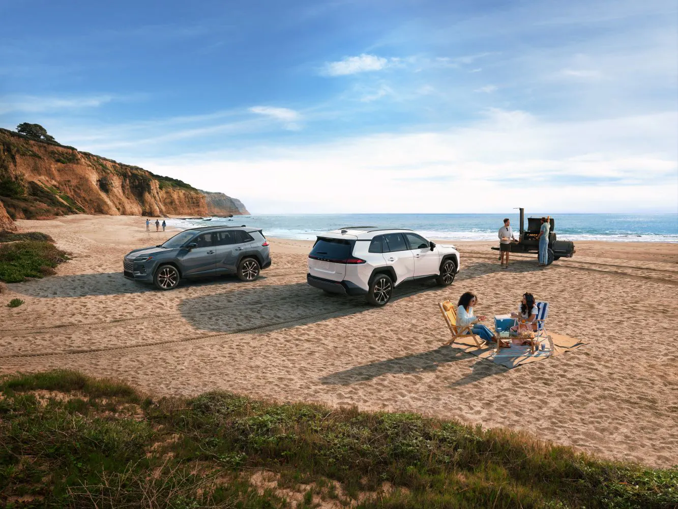 Toyota RAV4 Hybrid parked on the beach while friends relax nearby