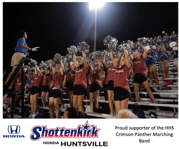 Screen-Shot-2023-07-06-at-3.49.51-PM A Huntsville High School Band conductor on ladder hand signals to band playing in bleachers