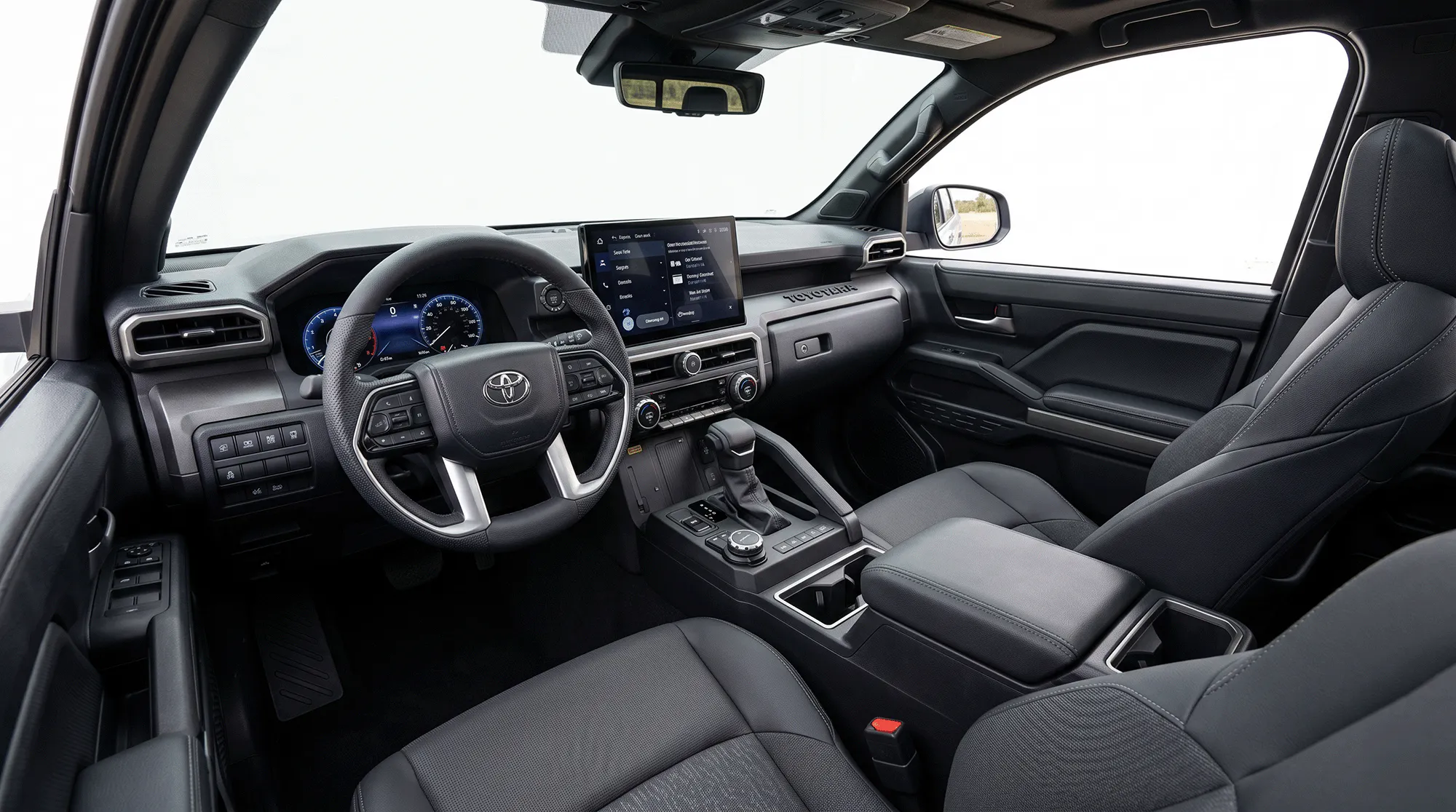 Interior of the 2026 Toyota Tacoma showing the dashboard, touchscreen, steering wheel, center console, and front seats