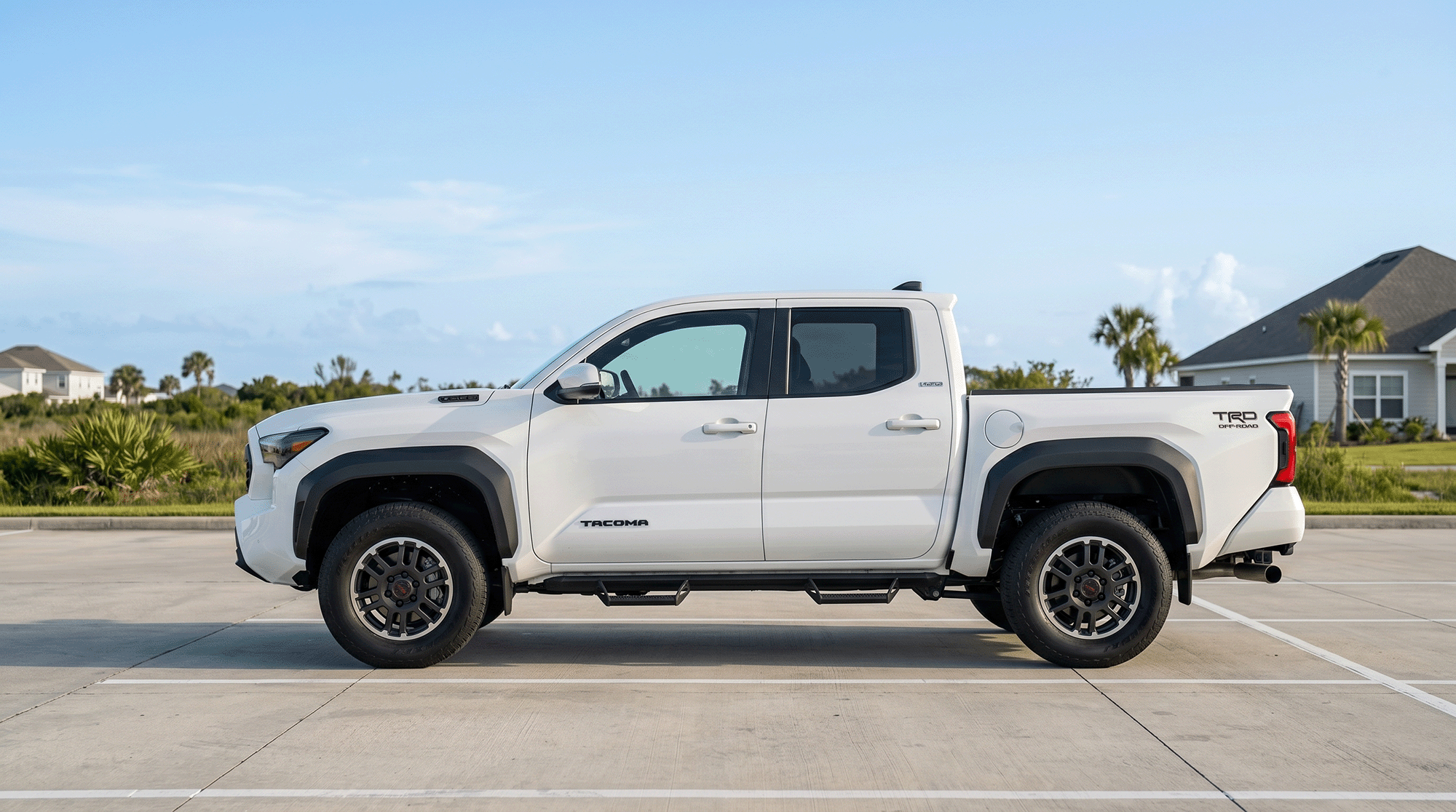 White 2026 Toyota Tacoma TRD Off-Road shown in full side profile in a sunny suburban Gulf Coast setting