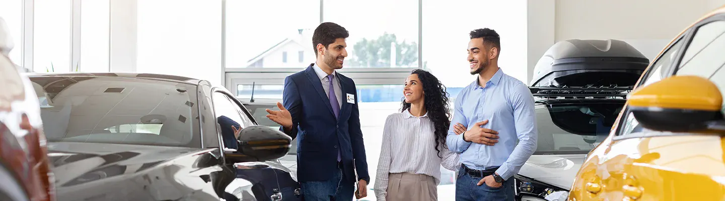 Young couple in vehicle showroom with sales associate