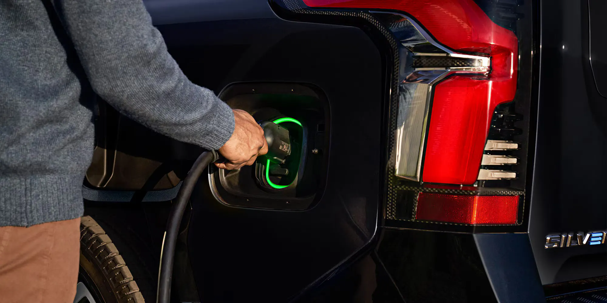 a view of a person using the charging port on the new 2026 chevy silverado EV