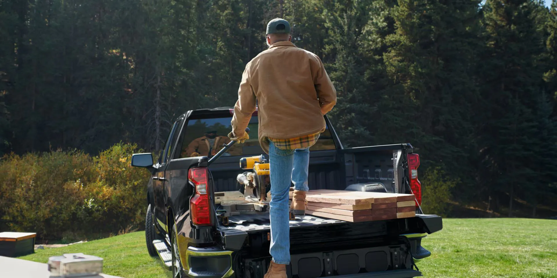 A man standing on the tailgate of a silverado 1500.