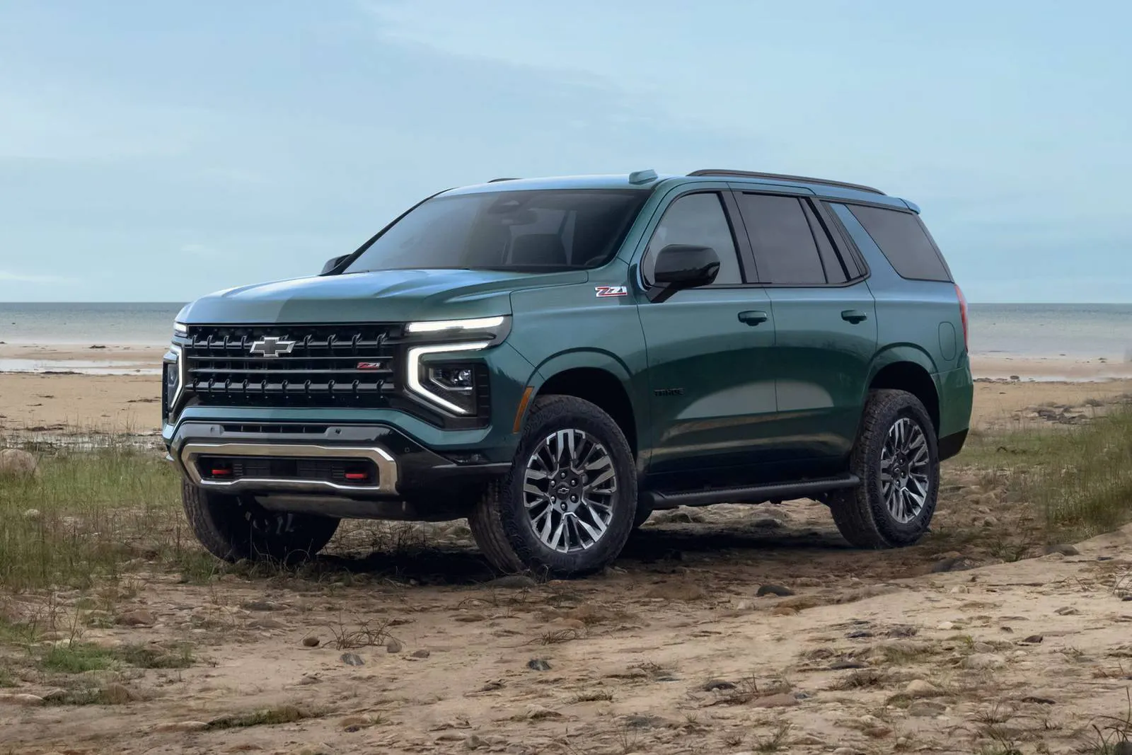 A green tahoe sitting parked off-road.