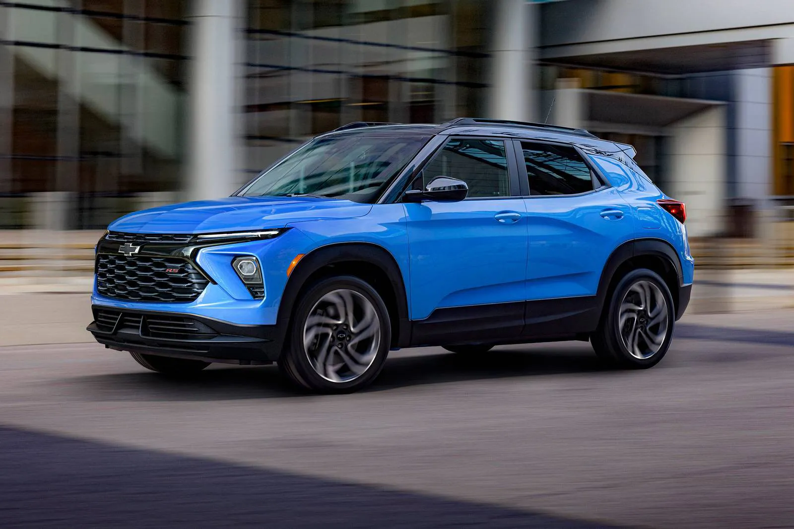 A blue trailblazer driving on the road.