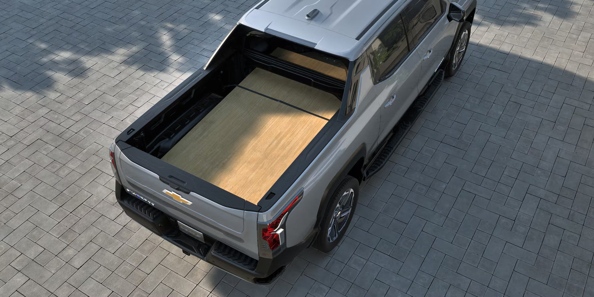2026-sev-lt-2x1-bed-functionality-4 a large ply wood panel in the bed of a silverado ev