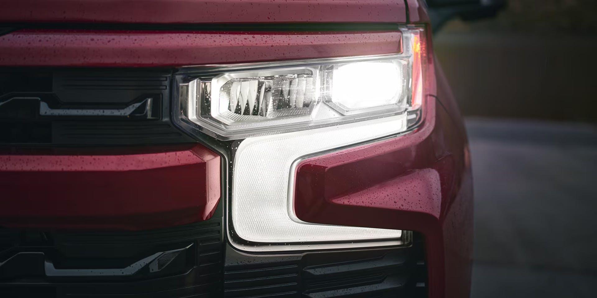 a red silverado 1500 showcasing the up close of the passenger front headlight. 