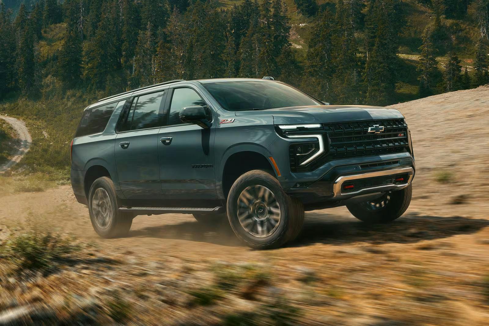 2026_chevrolet_suburban_4dr-suv_z71_fq_oem_2_1600x1067 chevy suburban driving up a hill in a forest