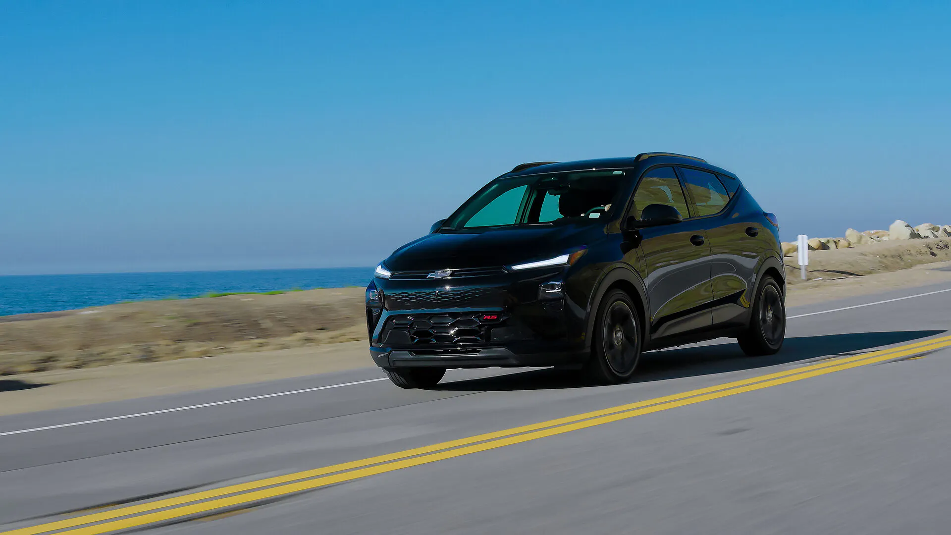 A black chevy bolt driving on the road.