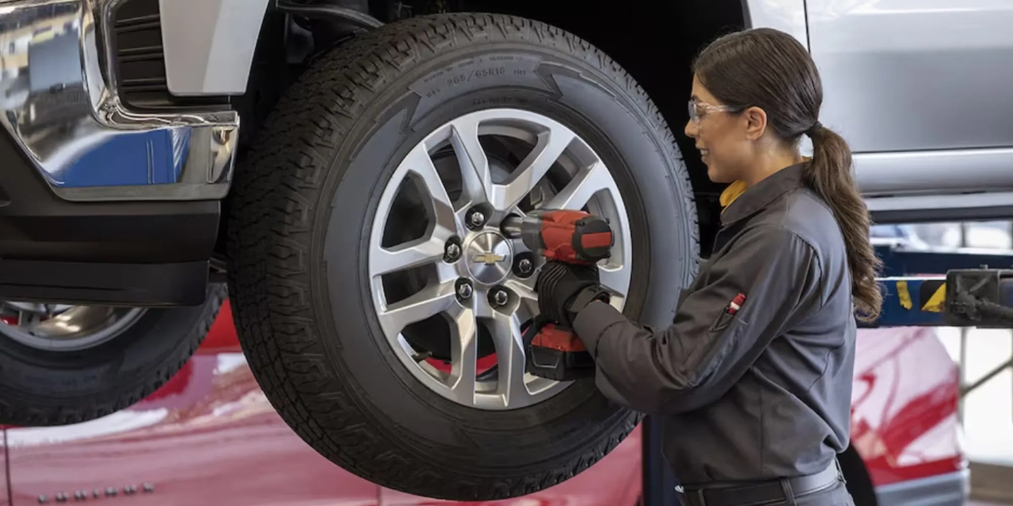 A woman changing the tires on a chevy.