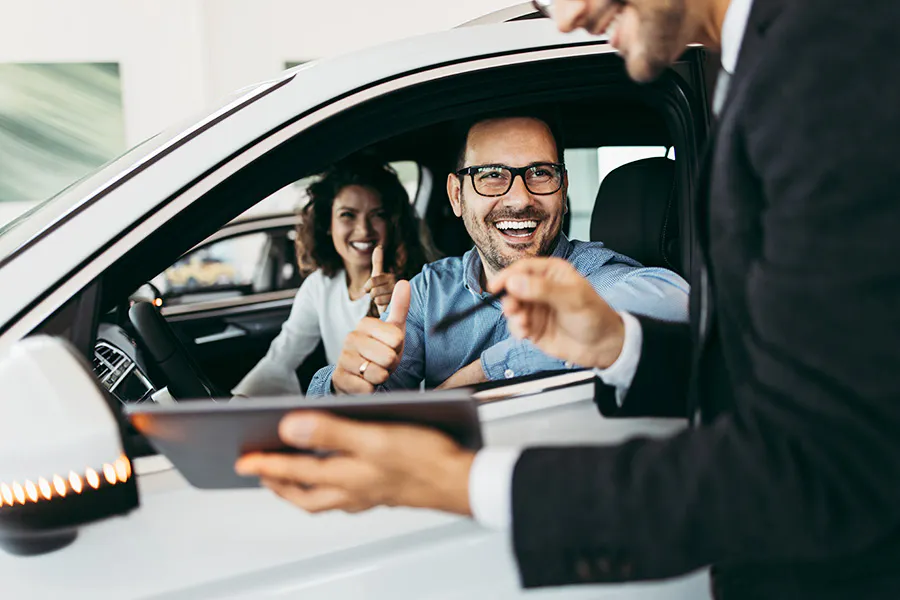 A man and woman smiling inside a car.